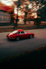 Porsche in Motion Through Autumn Hues, sleek red car moving down a tree-lined street, perfect for car wall art.