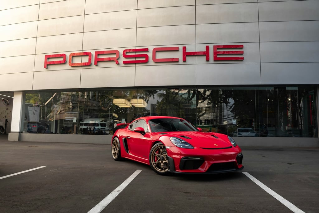 Red Cayman GT4 at Porsche Dealership, showcasing its vibrant red color and striking design in front of a modern dealership.