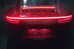 Crimson Porsche 911 in the Rain with gleaming LED taillights and raindrops creating a striking contrast on its body.