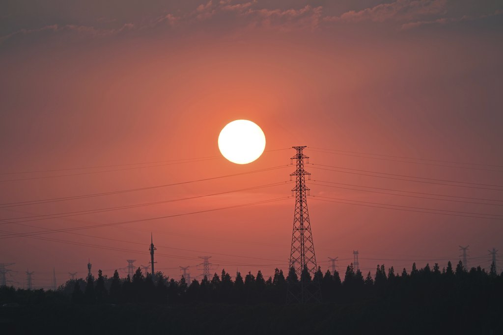 Q L - Silhouette of power lines against a vibrant sunset sky, illustrating energy and technology.