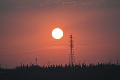 Q L - Silhouette of power lines against a vibrant sunset sky, illustrating energy and technology.
