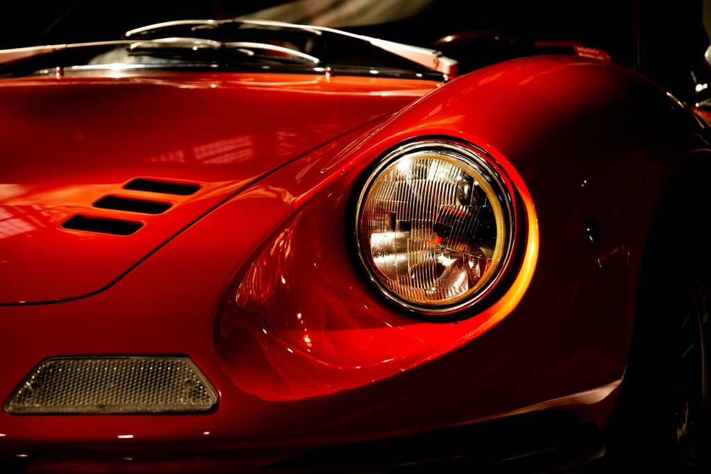 Close-up of Ferrari Dino 246 GT Timeless Design car wall art showcasing its iconic fender and glass headlight.
