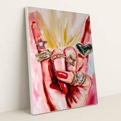 This artwork shows a hand with red nails wearing sparkly rings shaped like stars and a heart, set against pink painted brushstrokes, in a white frame.