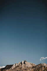 Alessio Cesario - A breathtaking view of a rocky mountain peak with a vast clear blue sky above, perfect for nature-inspired designs.