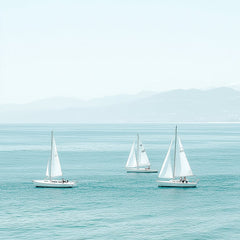 This artwork shows three white sailboats on calm turquoise water with mountains in the distance.
