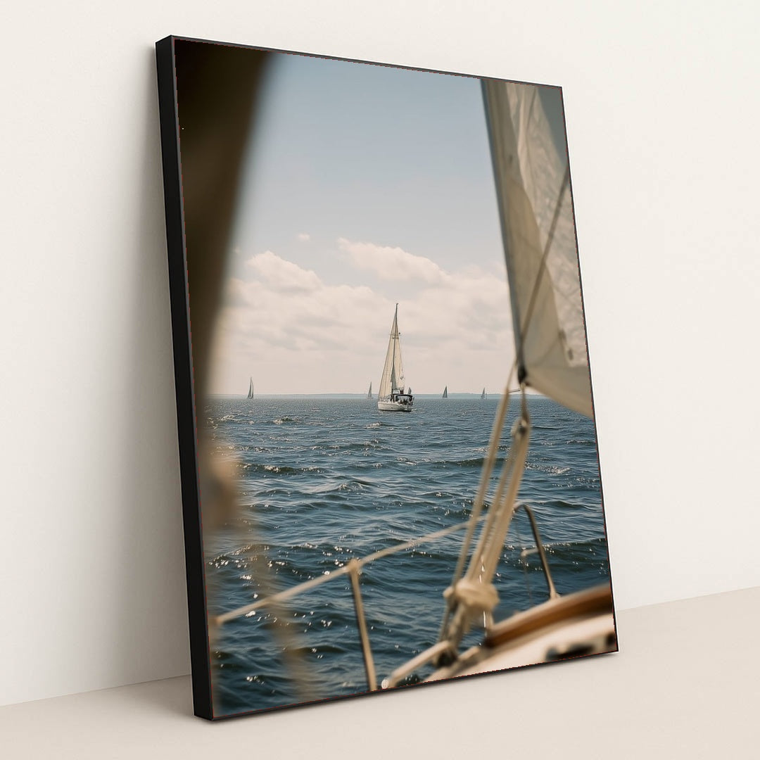 This artwork features a sailboat on deep blue water under a blue sky, viewed from another boat, in a black frame.