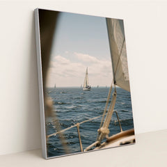This artwork features a sailboat on deep blue water under a blue sky, viewed from another boat, in a silver frame.