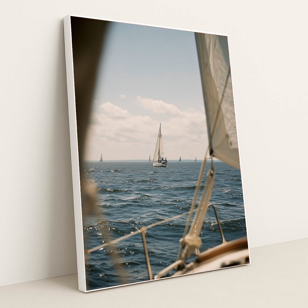 This artwork features a sailboat on deep blue water under a blue sky, viewed from another boat, in a white frame.
