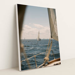This artwork features a sailboat on deep blue water under a blue sky, viewed from another boat, in a white frame.