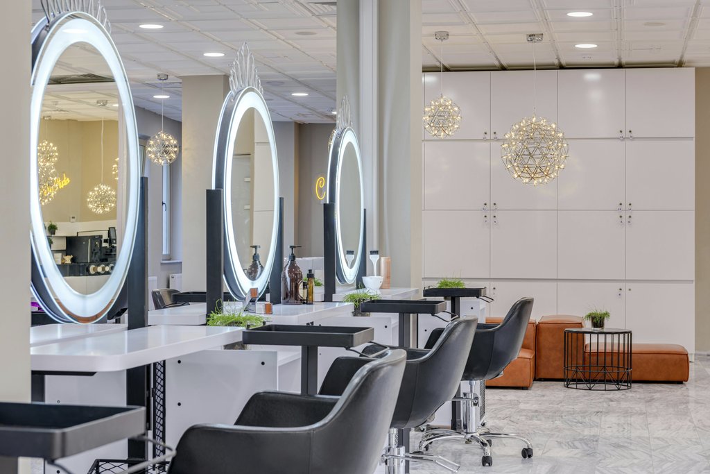 Max Vakhtbovycn - Bright and elegant hair salon interior featuring modern lighting and round mirrors for a chic and relaxing atmosphere.