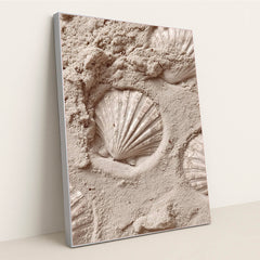 This artwork features white scallop shell imprints in smooth pale sand, in a silver frame.