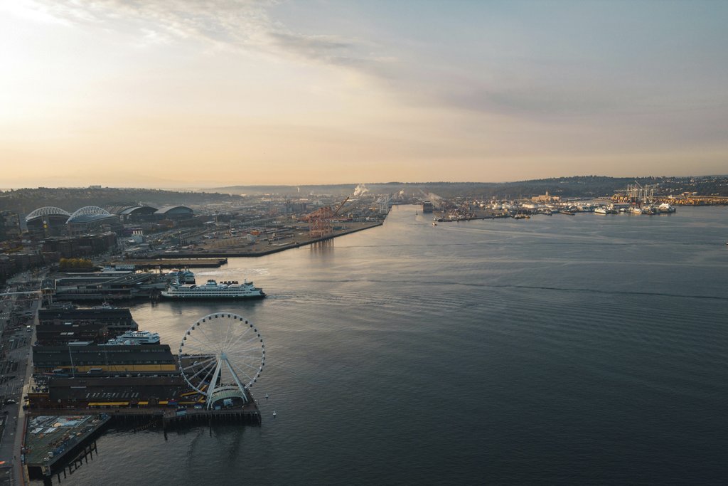 Willian Justen de Vasconcellos - Scenic aerial view of Seattle waterfront with ferris wheel at sunset, showcasing urban landscape.