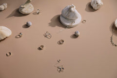 cottonbro studio - Stylish display of rings and earrings on a minimalist backdrop.