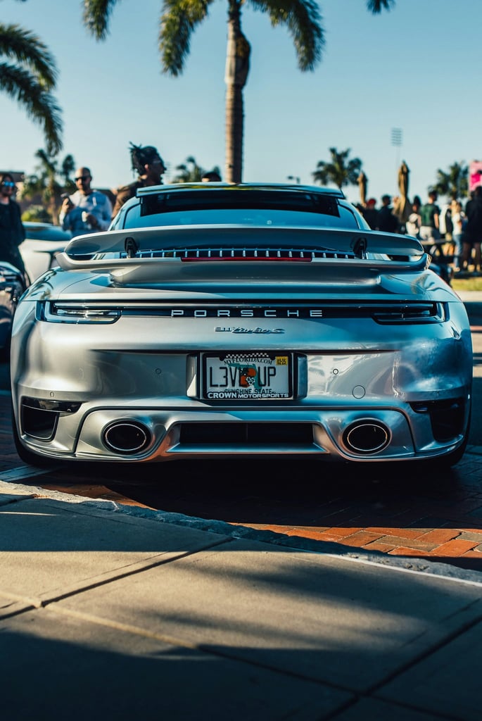 Porsche 911 Turbo S in Coastal Air captured from the rear, highlighting its sleek design and luxury features in a tropical setting.