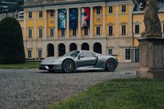 Porsche 918 Spyder at European Estate parked on gravel drive, showcasing its sleek design against grand architecture.