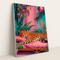 This artwork shows a lounging leopard on a pink couch surrounded by tropical plants and a sparkling disco ball, in a silver frame.