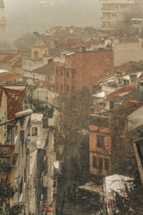 Unknown - A foggy view of Istanbul's urban landscape with red rooftops and historical architecture.