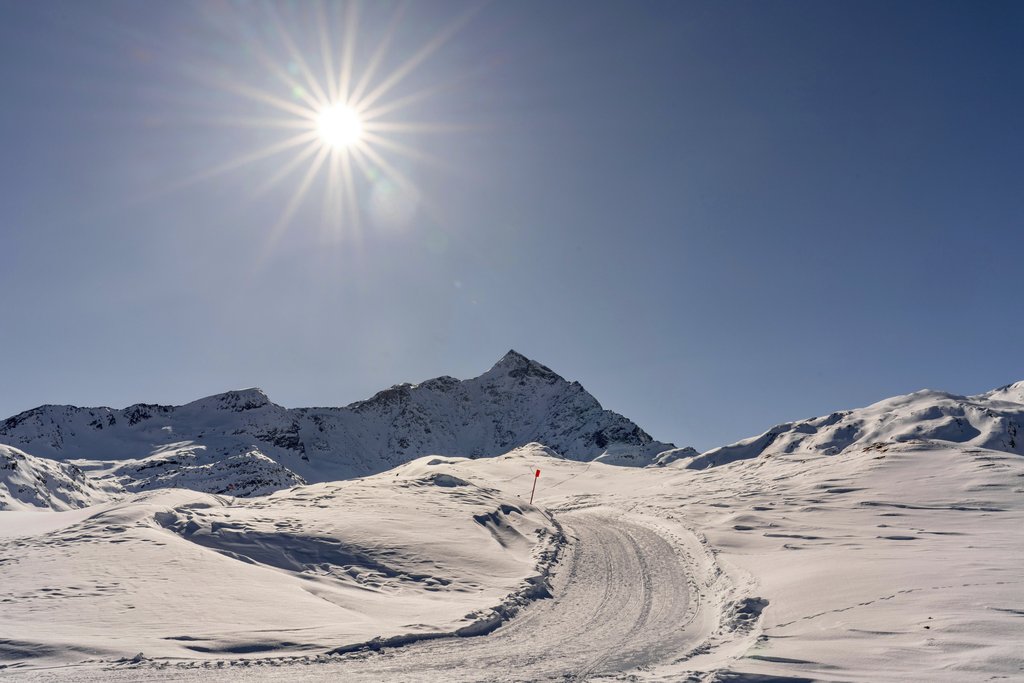 Susanne Jutzeler, suju-foto - A vibrant winter scene of sunlit snowy mountains and a winding path.