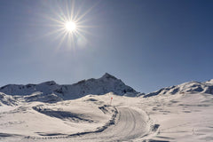Susanne Jutzeler, suju-foto - A vibrant winter scene of sunlit snowy mountains and a winding path.