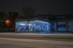 Mike Norris - Snowy night view of brightly lit gas station with neon lights and snow-covered street.