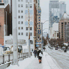 Qingju Wen - Snowy Seattle city street with Paramount Theatre in winter, showcasing urban architecture and passersby.