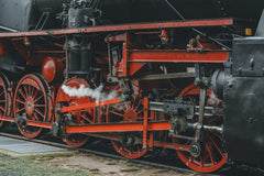 Masood Aslami - Detailed view of vintage steam train wheels showing intricate engineering and steam emission.
