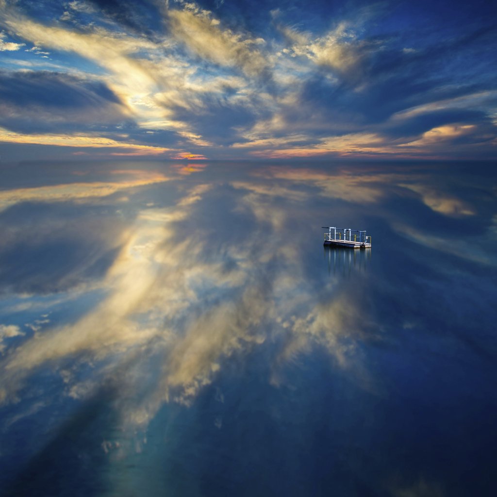 Floating Dock on Calm Lake at Dusk with Dramatic Cloud Reflections by Anonymous