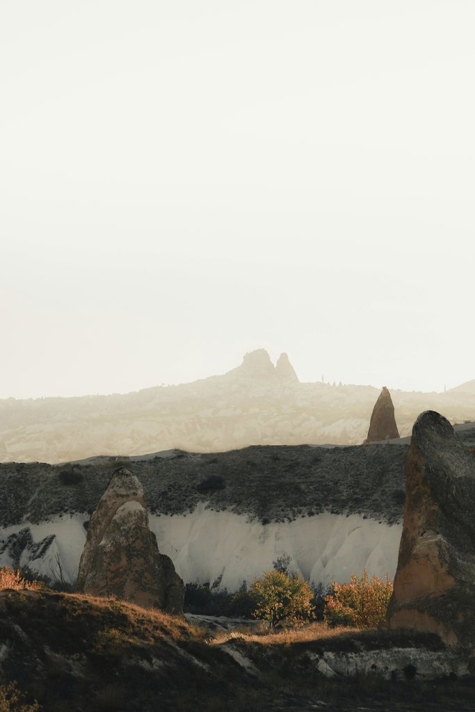Emir Anık - A captivating view of rugged rock formations under a misty sky, evoking a sense of mystery.