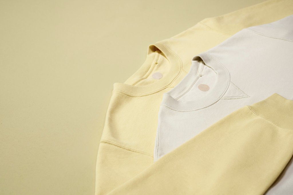 Ron Lach - Pastel-colored sweatshirts arranged on a neutral background, emphasizing casual fashion style.