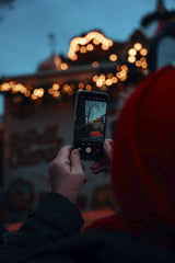 Christiyana - A person photographing Berlin's Christmas market ambiance with a smartphone during the festive season.