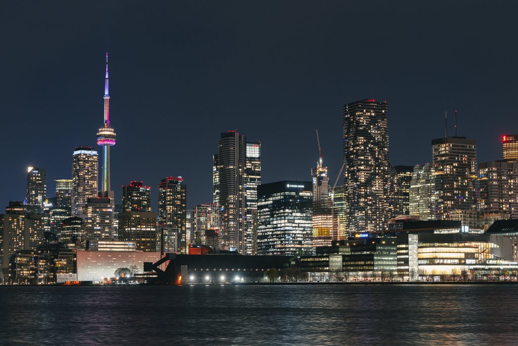 Mike Norris - Vibrant night view of Toronto skyline featuring the illuminated CN Tower reflecting on the water.