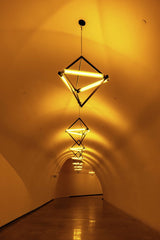 Adrian Newell - Dimly lit tunnel corridor with glowing geometric lamps creating a warm ambiance.