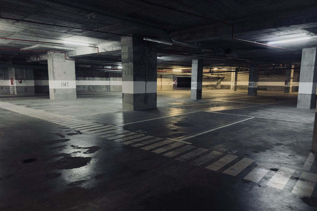 Pedro Dias - A moody underground parking garage featuring empty spaces and puddles on the floor.