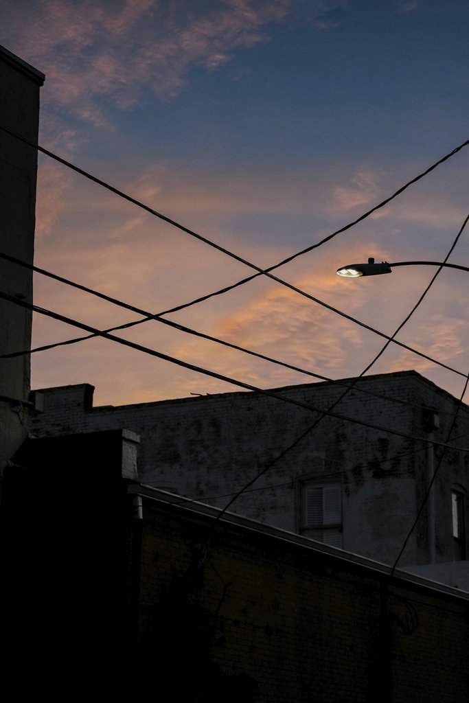 Connor McManus - A moody urban scene featuring a silhouetted streetlamp against a sunset sky.