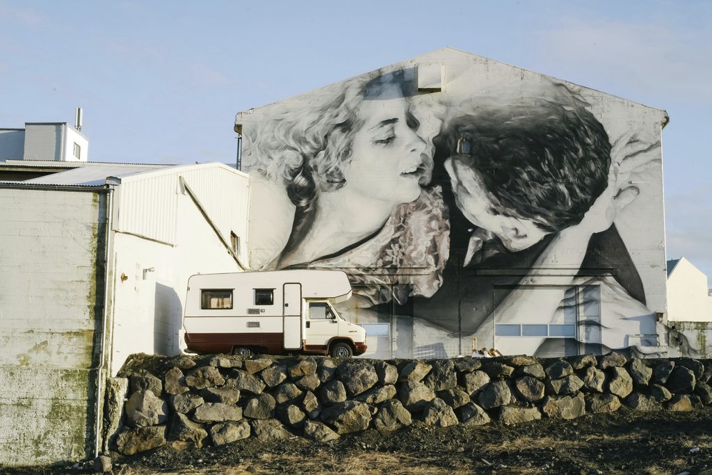 ArtHouse Studio - A campervan parked beside a large grayscale mural of a couple on an industrial building wall.
