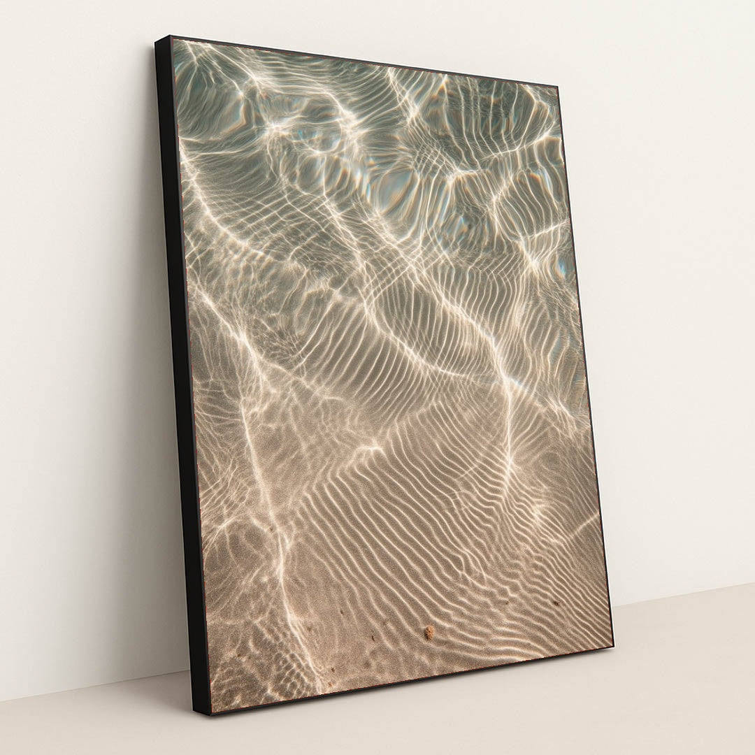 This artwork features shimmering sunlight patterns rippling across sandy underwater textures, displayed in a black frame.