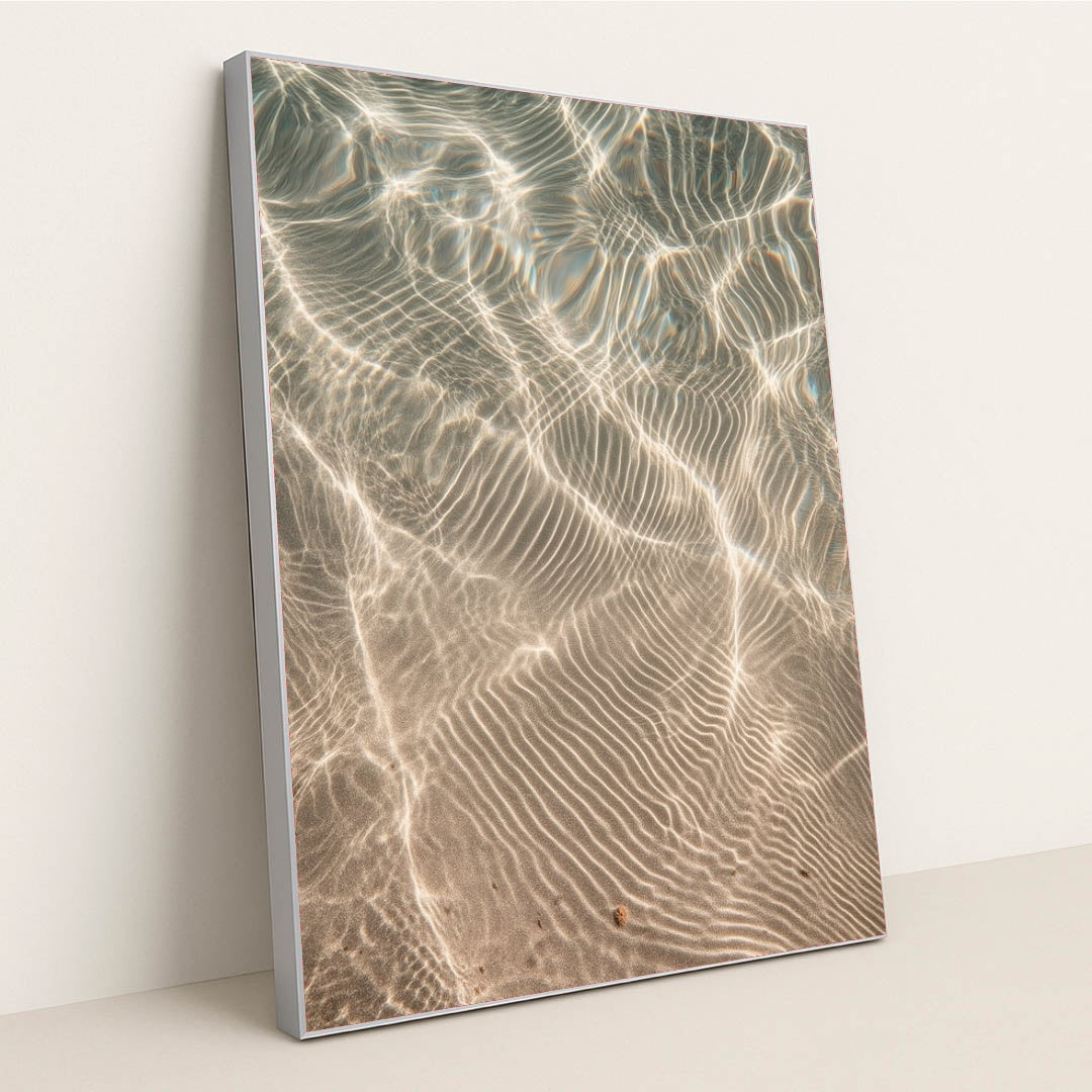 This artwork features shimmering sunlight patterns rippling across sandy underwater textures, displayed in a silver frame.