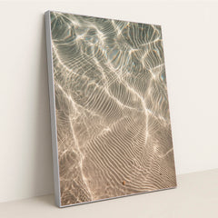 This artwork features shimmering sunlight patterns rippling across sandy underwater textures, displayed in a silver frame.