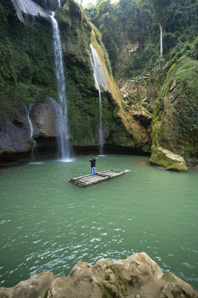 Nguyen Khuong - A person on a raft embraces nature under a waterfall in Sơn La, Vietnam.