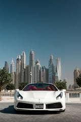 Ferrari 488 Spider in Dubai showcasing a sleek white design with a red interior against a stunning city skyline.
