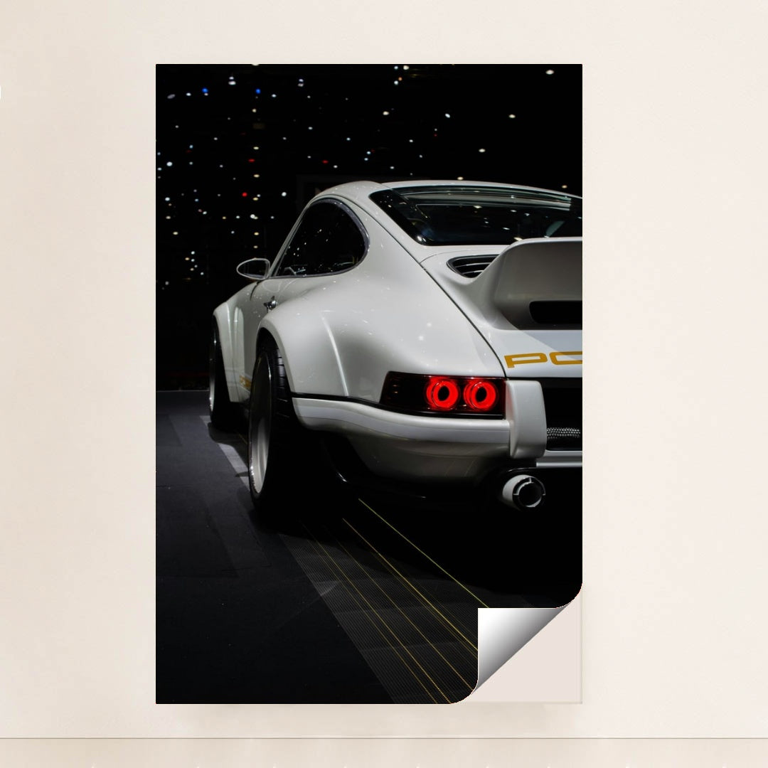 This photo shows the rear of a white Porsche sports car with a large wing, illuminated taillights, and starry reflections, minimalist unframed style.