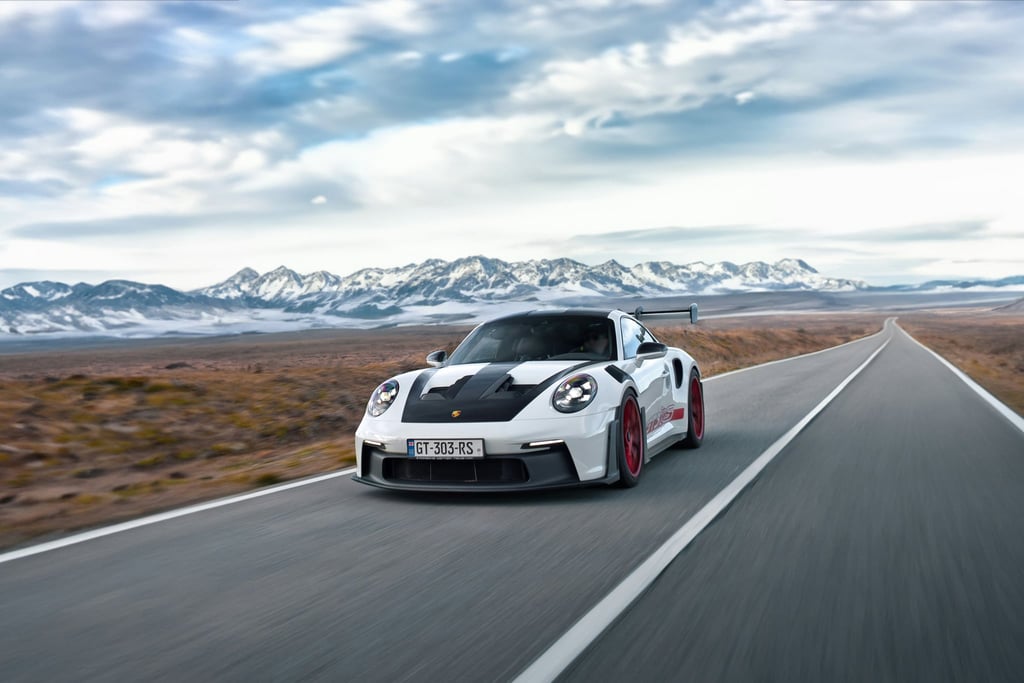 Porsche 911 GT3 RS on Desert Highway, white car with red wheels racing on a desert road with mountains in the background.