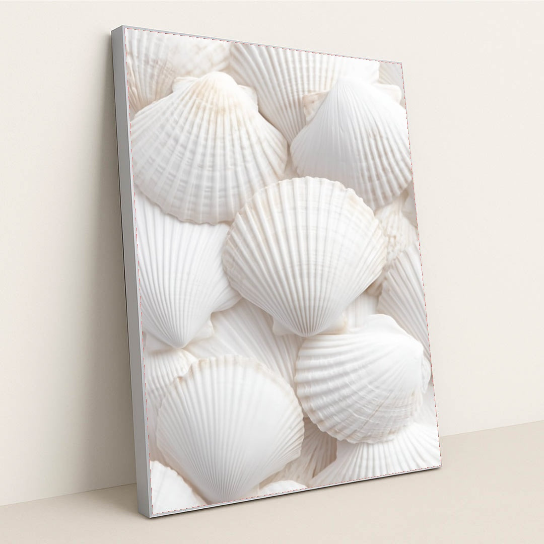 This artwork shows an arrangement of white scallop shells layered in a soft, airy composition, in a silver frame.