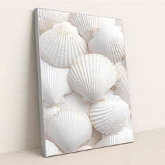 This artwork shows an arrangement of white scallop shells layered in a soft, airy composition, in a silver frame.