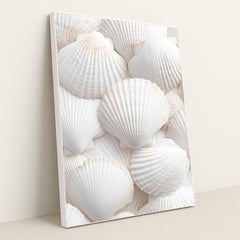 This artwork shows an arrangement of white scallop shells layered in a soft, airy composition, in a white frame.