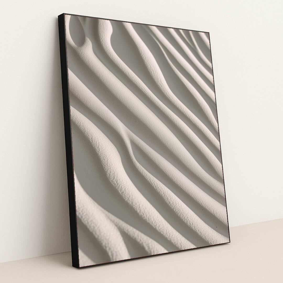 This artwork shows smooth, wavy lines of pale sand in soft sunlight, in a black frame.