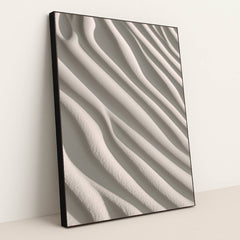This artwork shows smooth, wavy lines of pale sand in soft sunlight, in a black frame.