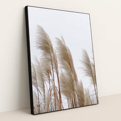 This artwork features tall beige pampas grass stems against a pale sky, in a black frame.