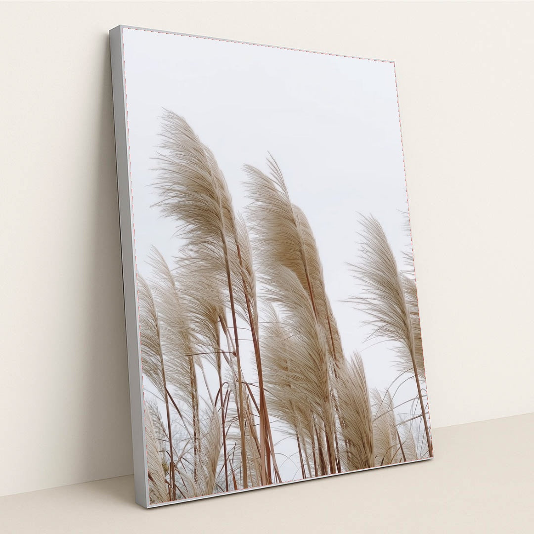 This artwork features tall beige pampas grass stems against a pale sky, in a silver frame.