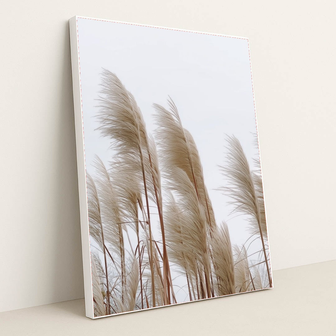 This artwork features tall beige pampas grass stems against a pale sky, in a white frame.
